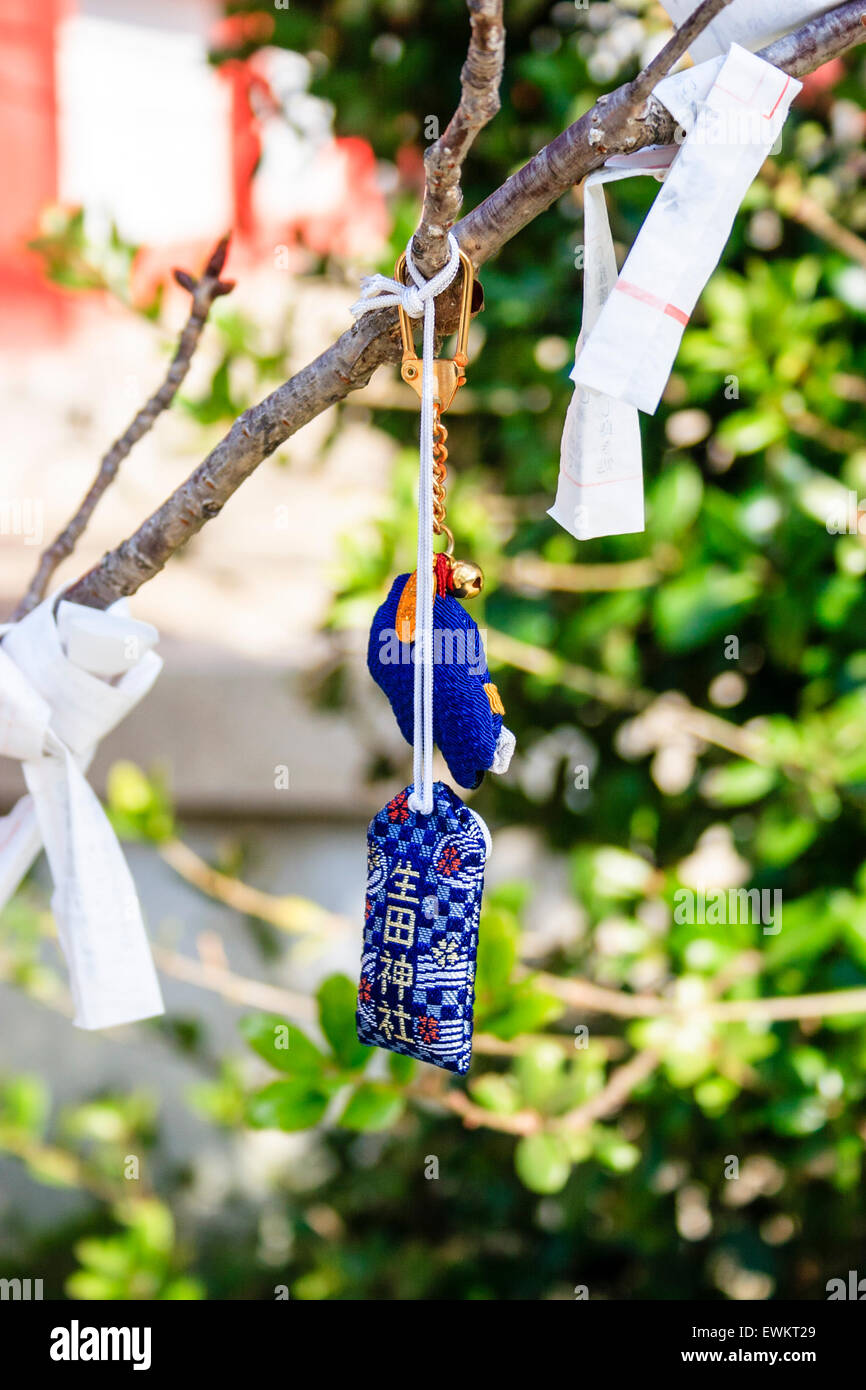 Close up of bad luck Omikuji fortune paper slips tied to twigs and small branches of a tree at the Ikuta Shinto Shrine in Kobe. Stock Photo