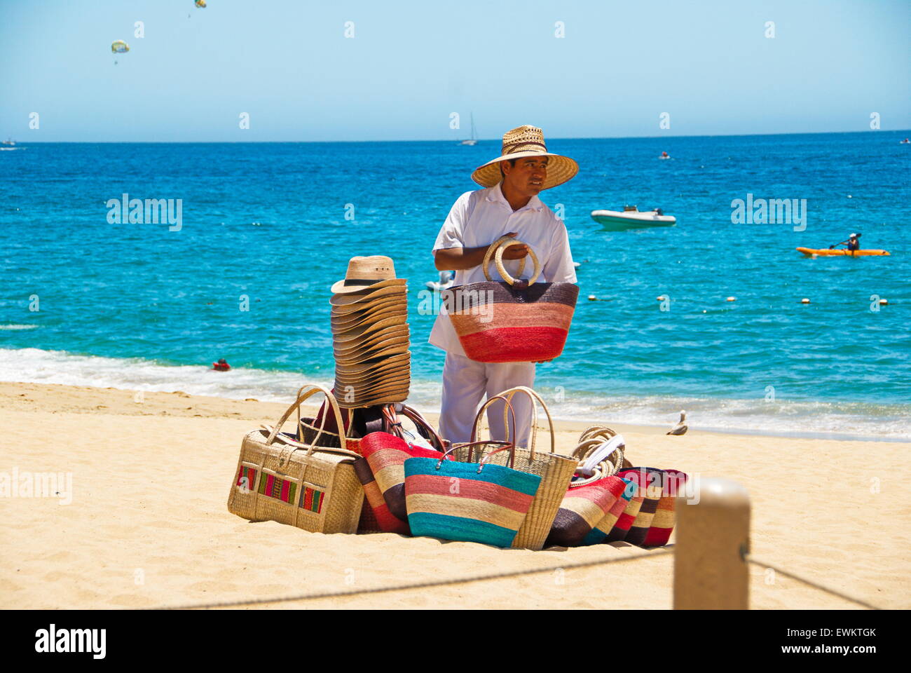 Local Mexican man selling straw bags and hats on beach in Cabo San