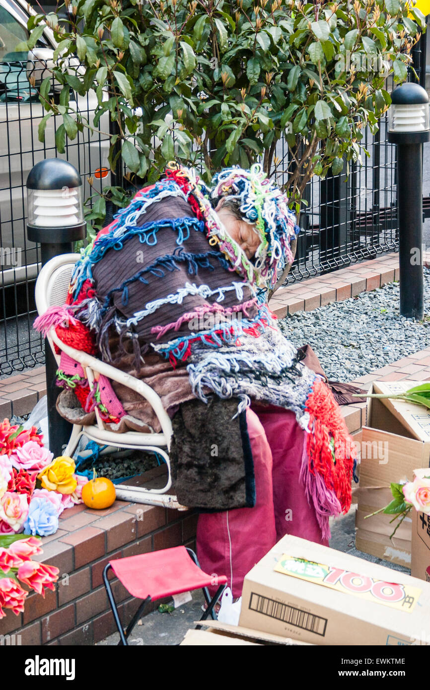 Japan, Osaka. Japanese homeless old woman, dressed with wool around outfit,  sitting asleep on street surrounded by boxes of vegetables she is selling  Stock Photo - Alamy