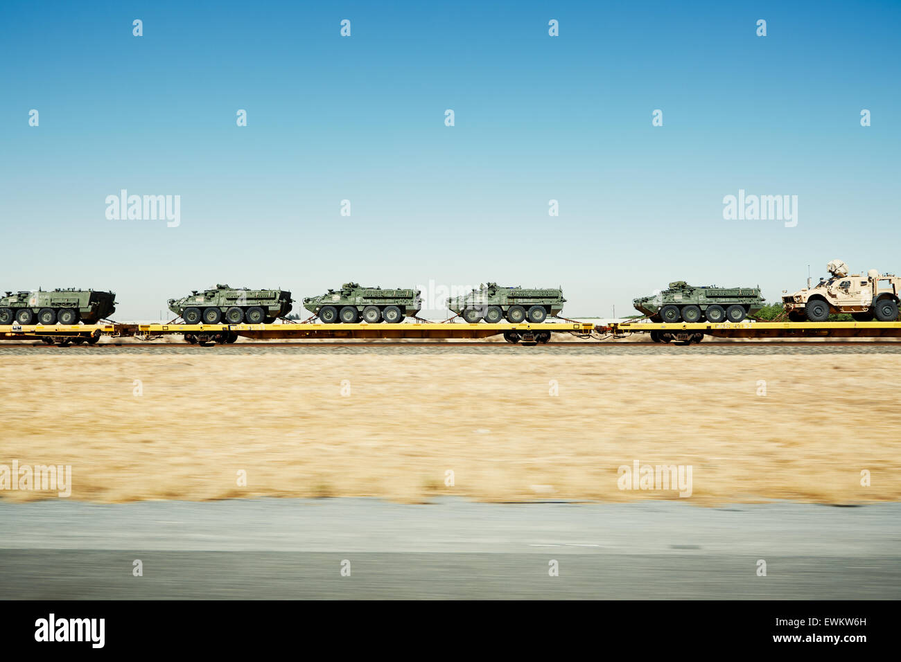 An endless cargo of tanks on a train pulled down tracks in an empty dry landscape. Stock Photo