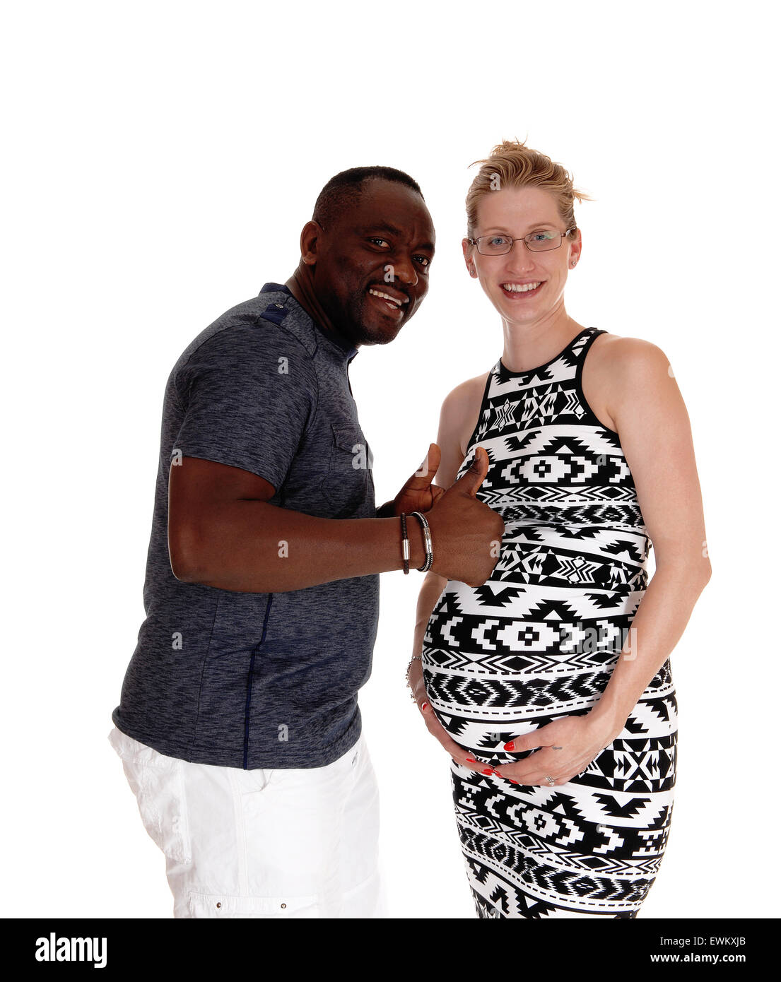 A mixed couple, black man Caucasian woman pregnant standing for white background with thumps up and very happy. Stock Photo
