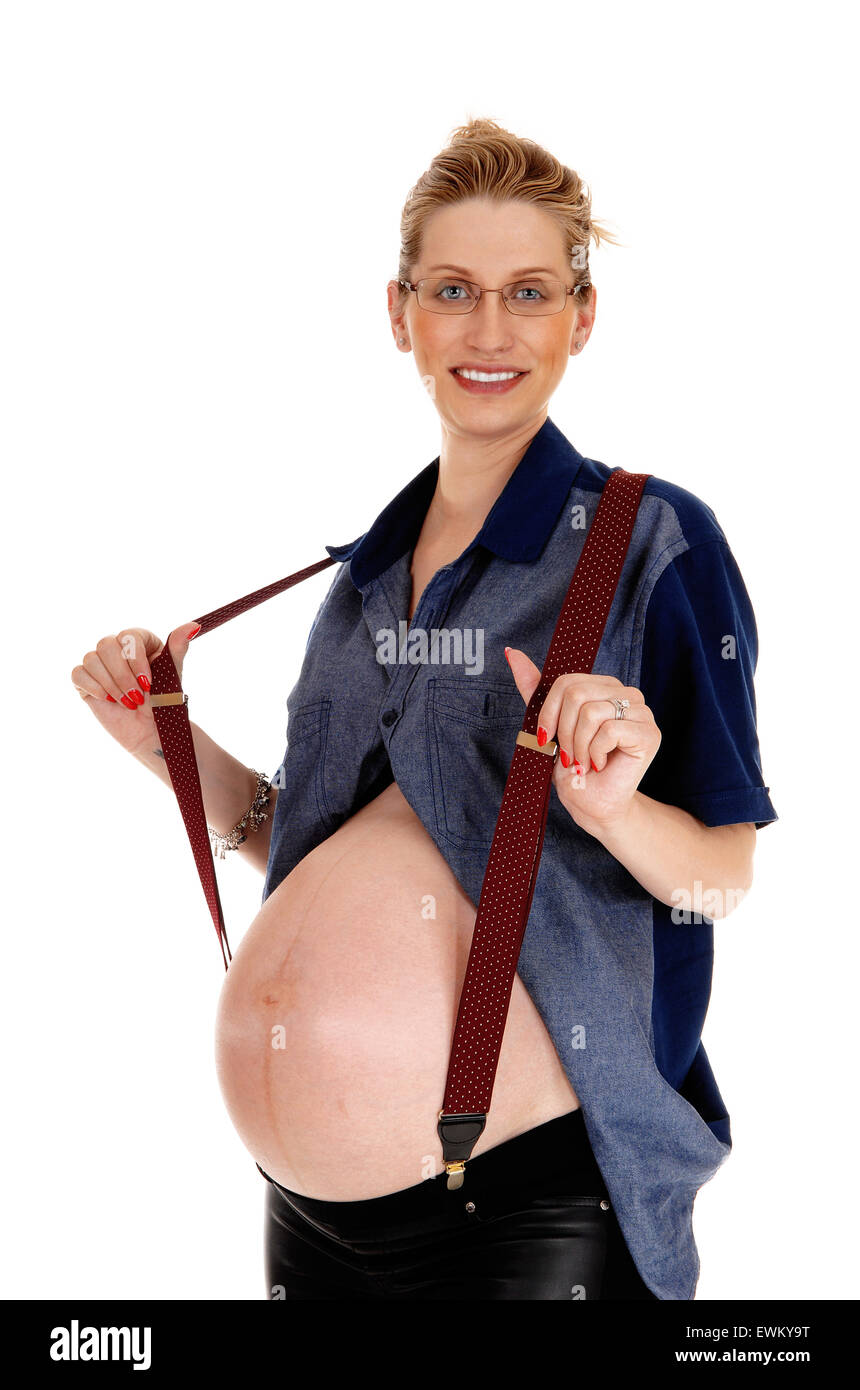 A happy Caucasian pregnant woman, showing her baby tummy, holding her suspender, isolated for white background. Stock Photo