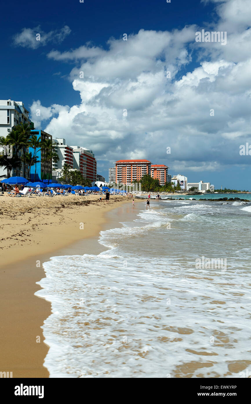 El Condado Beach, blue umbrellas and skyline, El Condado, San Juan, Puerto Rico Stock Photo