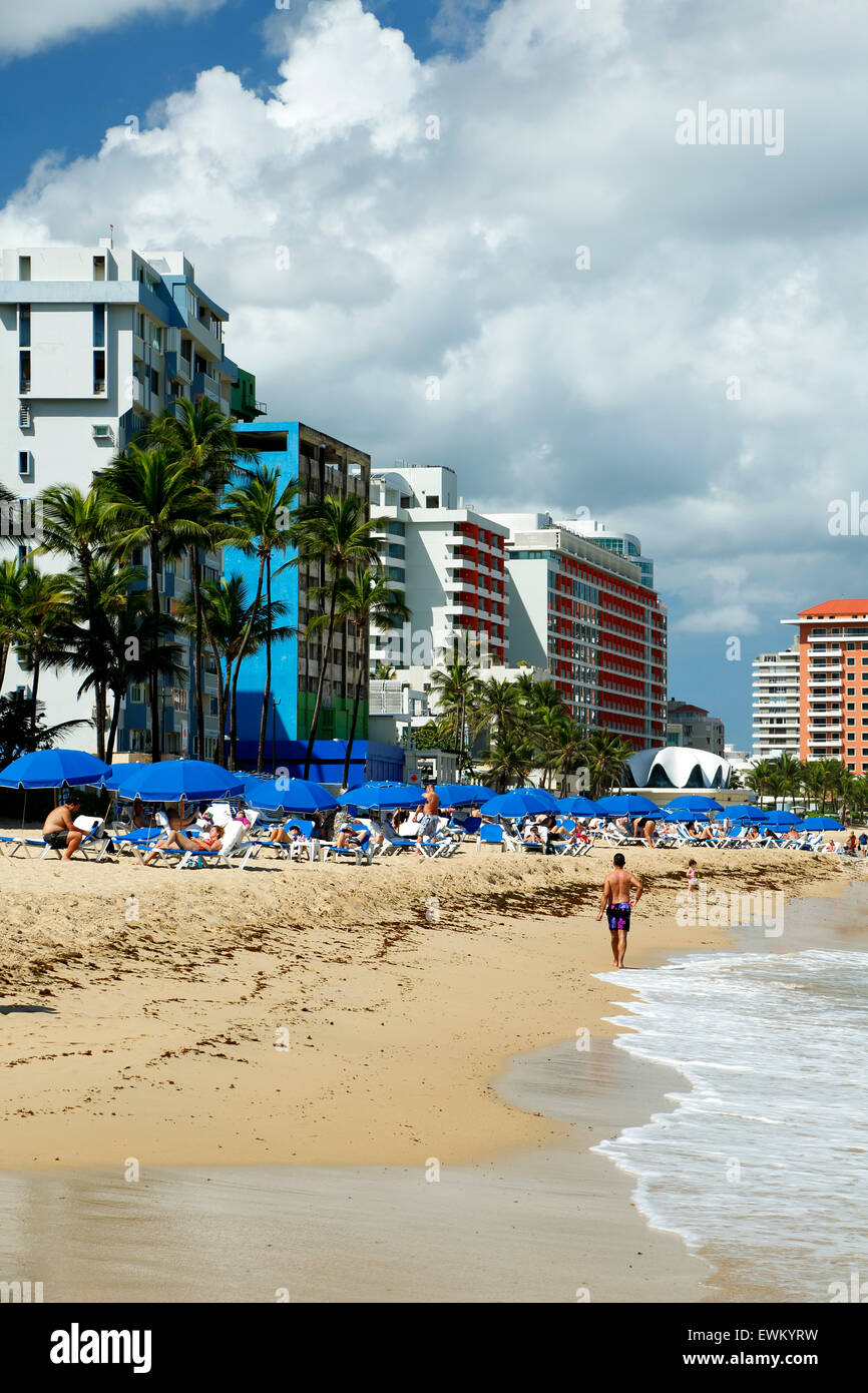 El Condado Beach, blue umbrellas and skyline, El Condado, San Juan, Puerto Rico Stock Photo