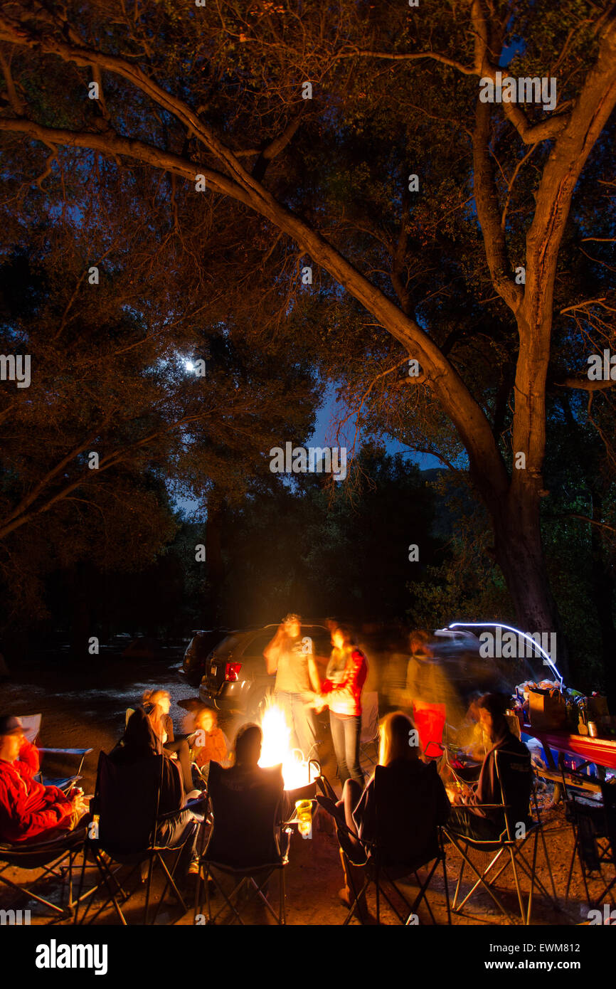 A group of friends sits around a campfire telling stories in Los Padres National Forest. Stock Photo