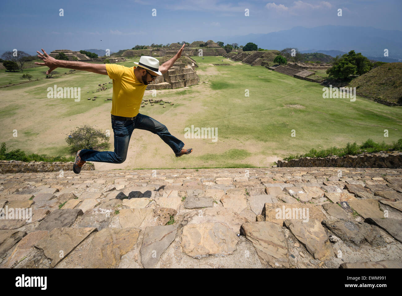 Hispanic man jumping for joy on the stone steps of Monte Alban ruins in Mexico Stock Photo