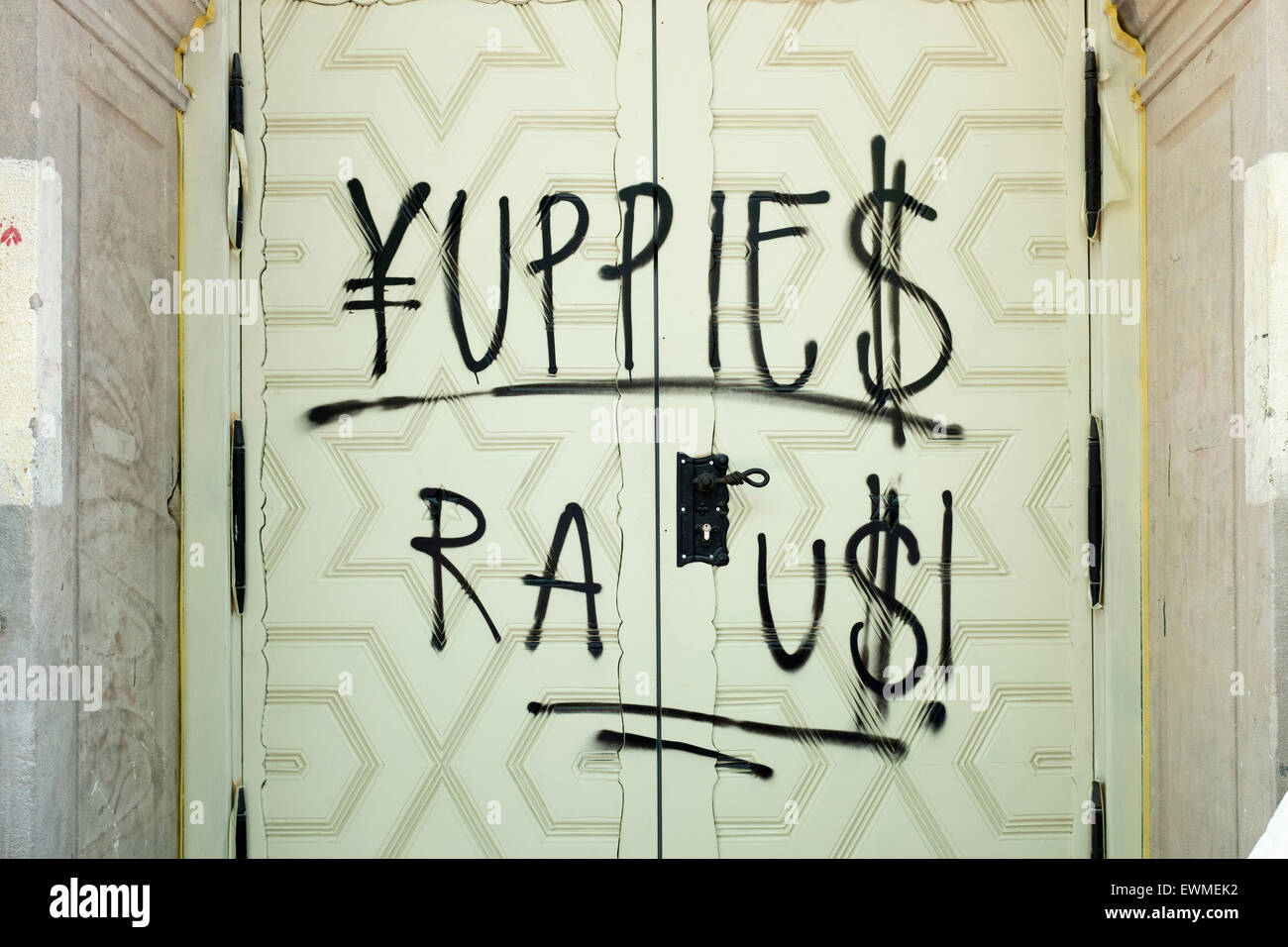 Graffiti "Yuppies Raus " or "Yuppies Out" painted on door of renovated historic building in gentrified Prenzlauer Berg Berlin Ge Stock Photo