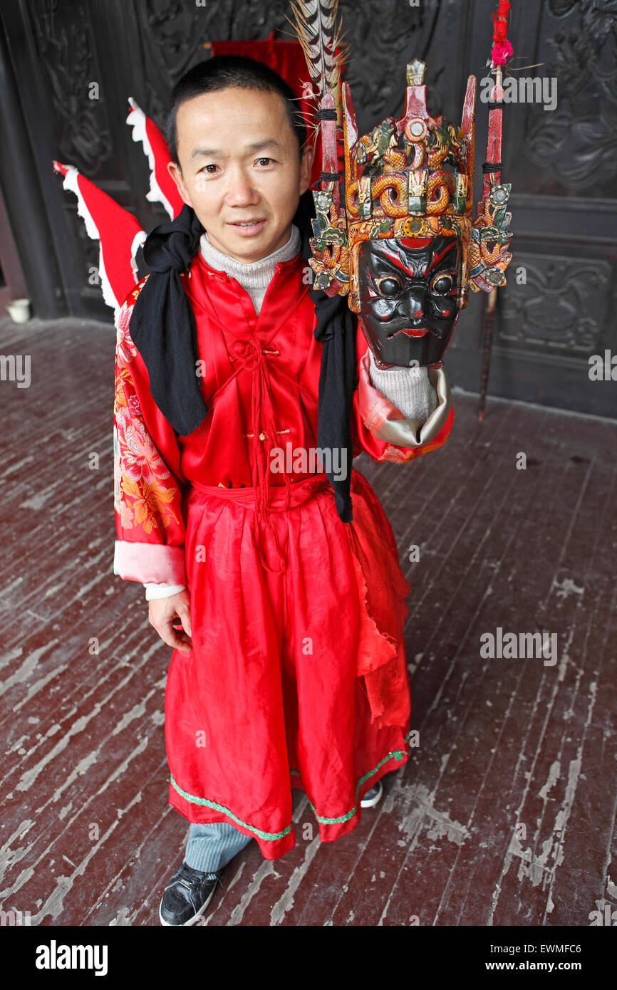 Mask dancer in CiYun Temple holding a traditional mask, Qingyan