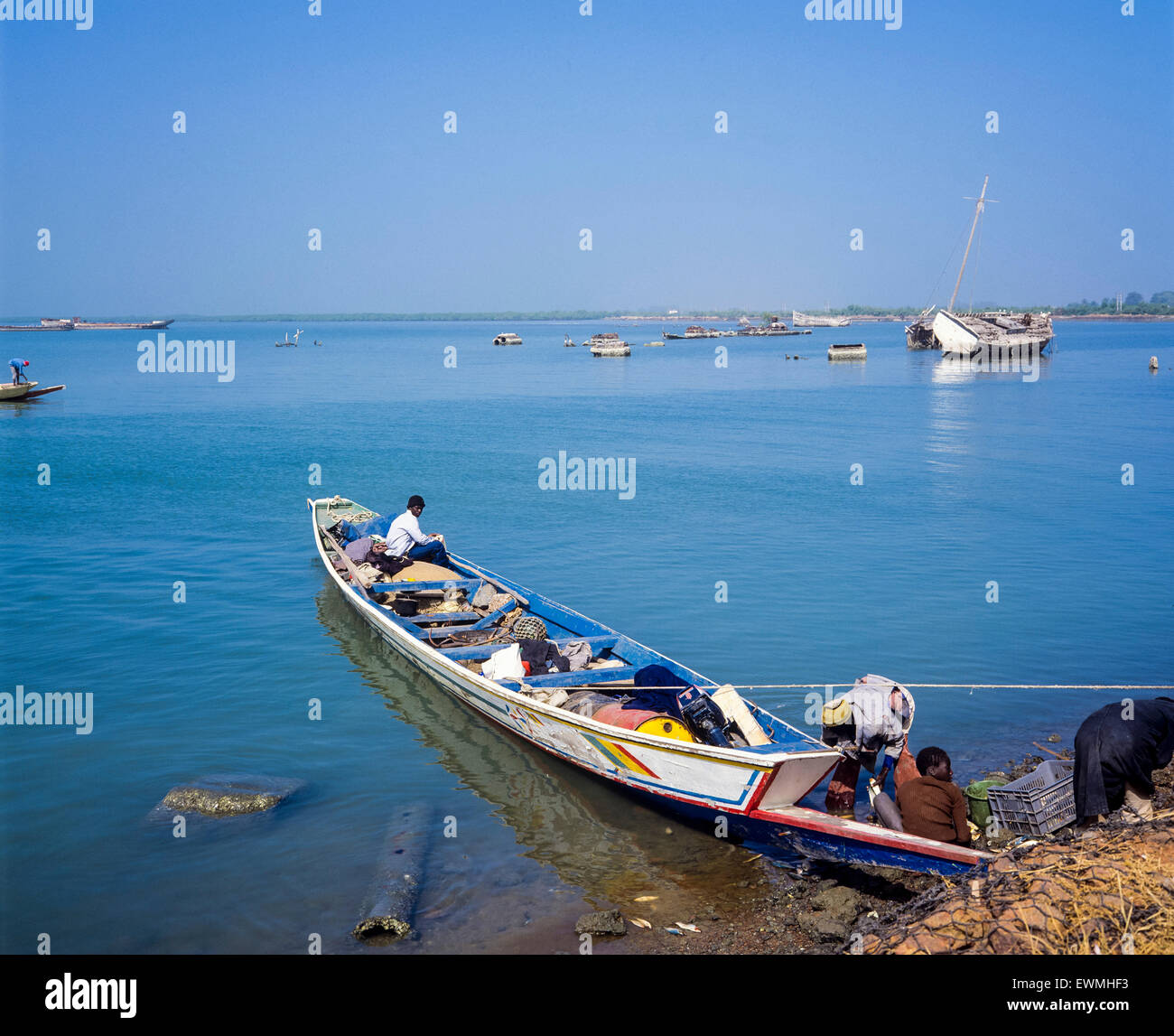 Women in colorful traditional clothes wait to collect fish from boat on  beach Bakau The Gambia Stock Photo - Alamy