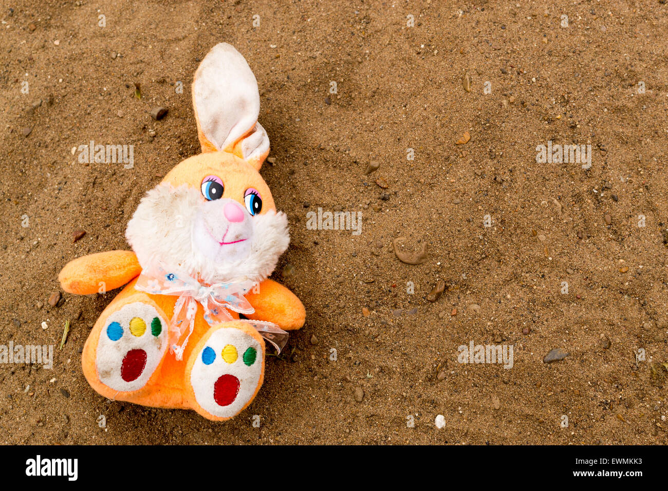 Muticolred rabbit toy left in an empty sand pit Stock Photo - Alamy
