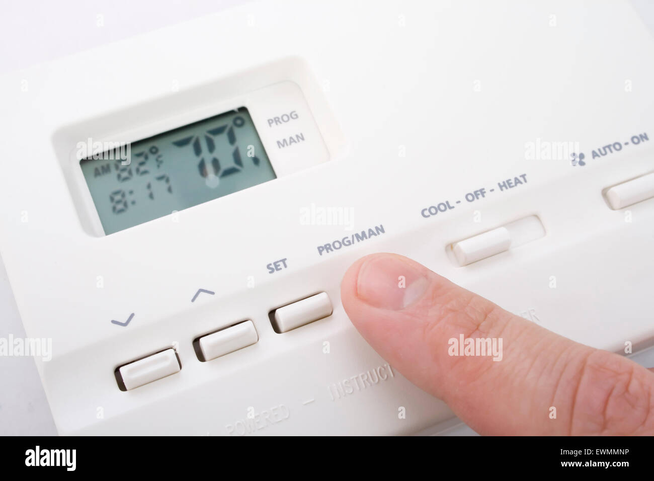 Closeup shot of male hand adjusting thermostat to 70 degrees Stock Photo