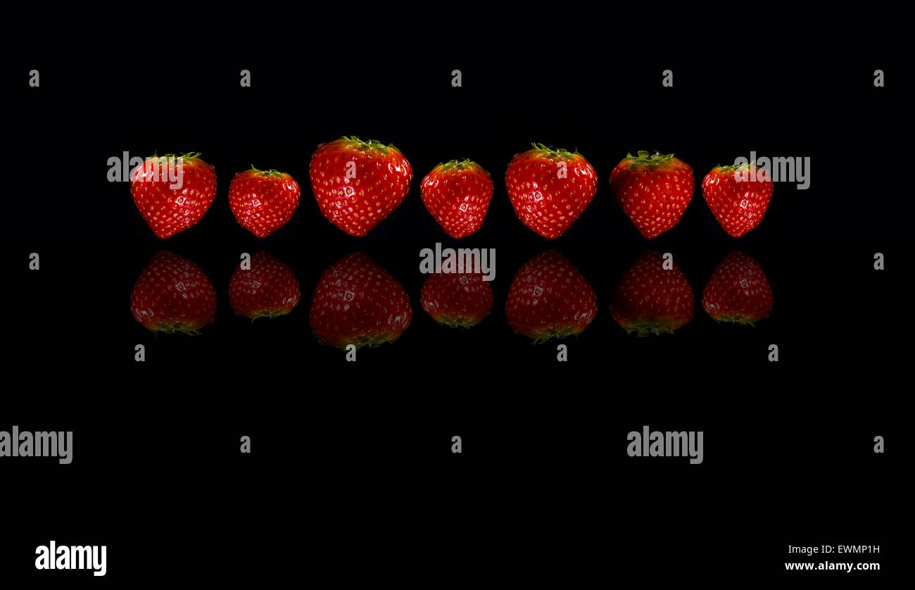 Seven Strawberries reflected on a black background Stock Photo - Alamy