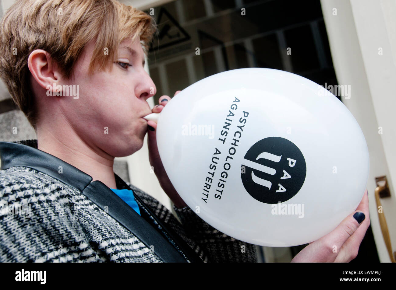March against austerity, London June 20th 2015. A woman (a psychologist) blows up a balloon saying 'Psychologists against auster Stock Photo