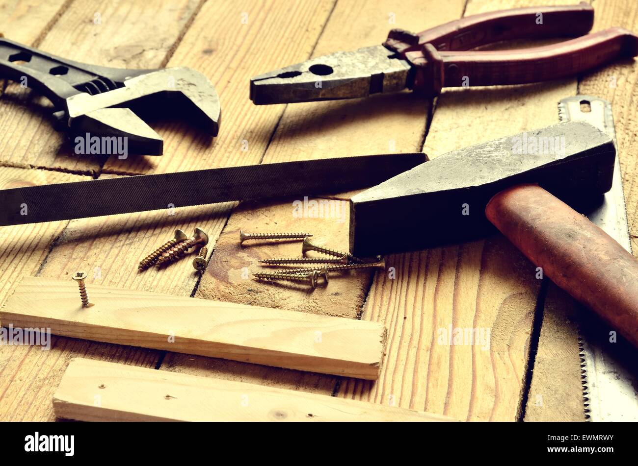 Renovation tools. Hammer, flat file, pliers, monkey wrench, screws, boards and blade on natural wooden background. Stock Photo