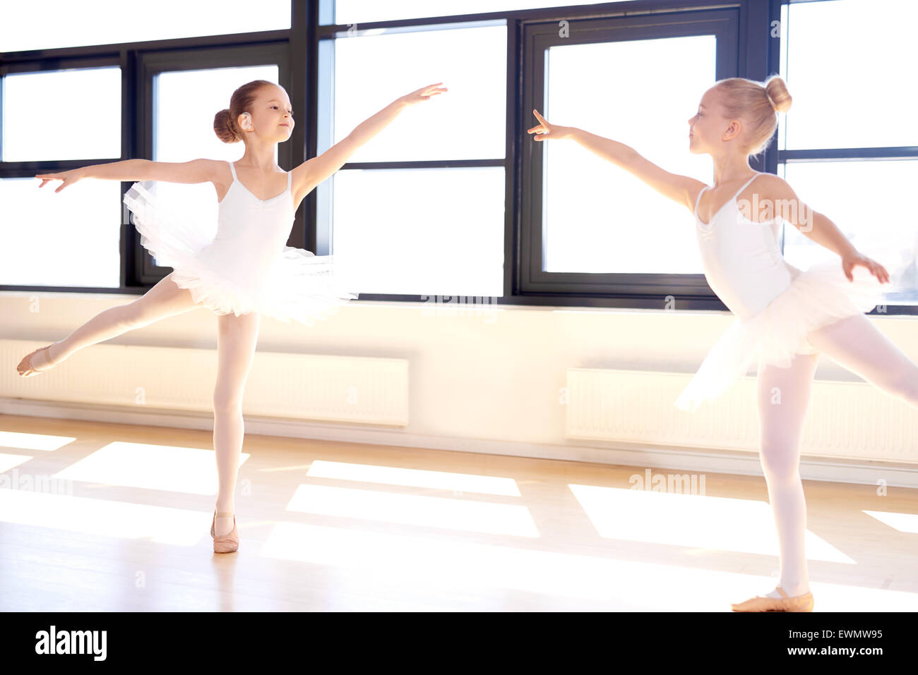 Two graceful little girls practicing a choreographed ballet in a classical ballet studio as they fulfil their dreams to become a Stock Photo