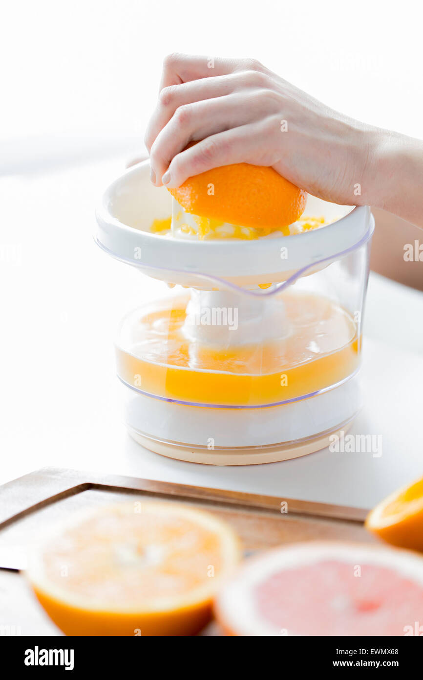 woman with squeezer squeezing orange juice at home Stock Photo
