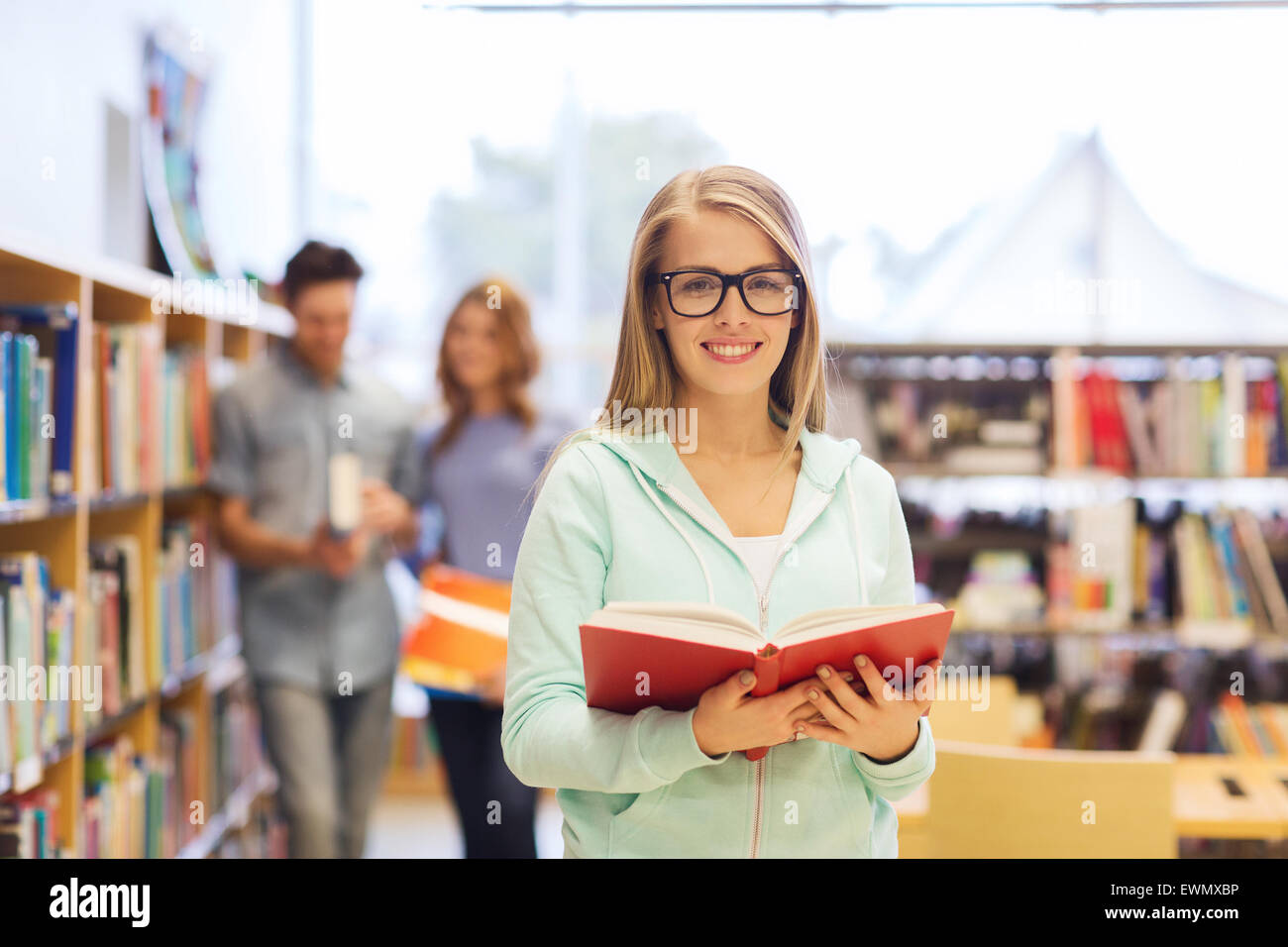 happy student girl or woman with book in library Stock Photo - Alamy