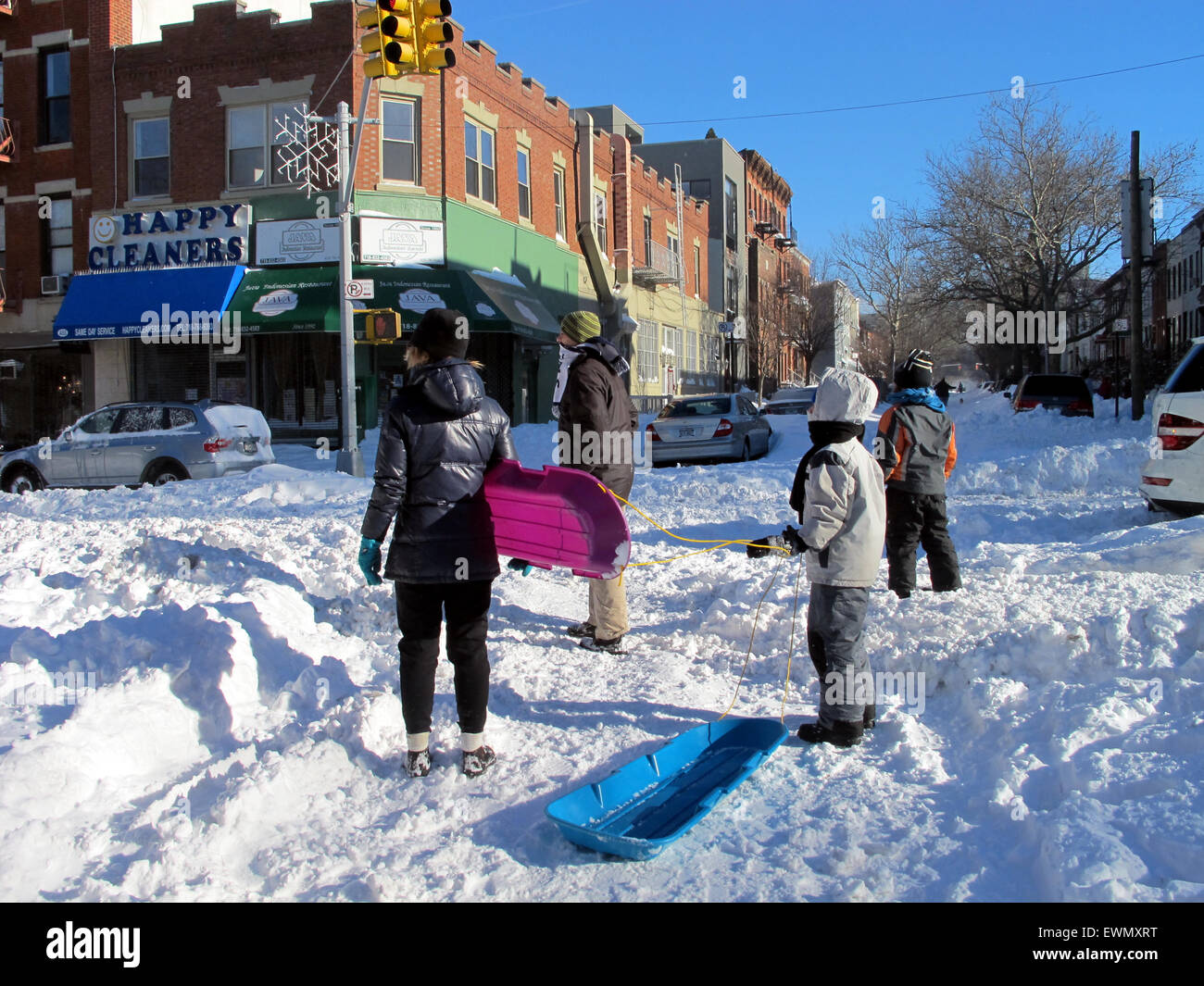 Family with sledges in snow covered street, Brooklyn, NYC, USA Stock