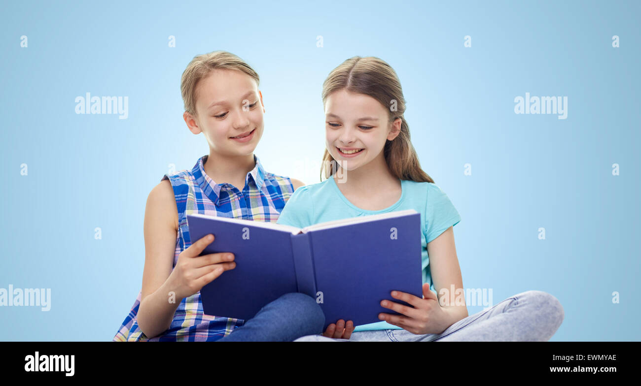 two happy girls reading book over blue background Stock Photo
