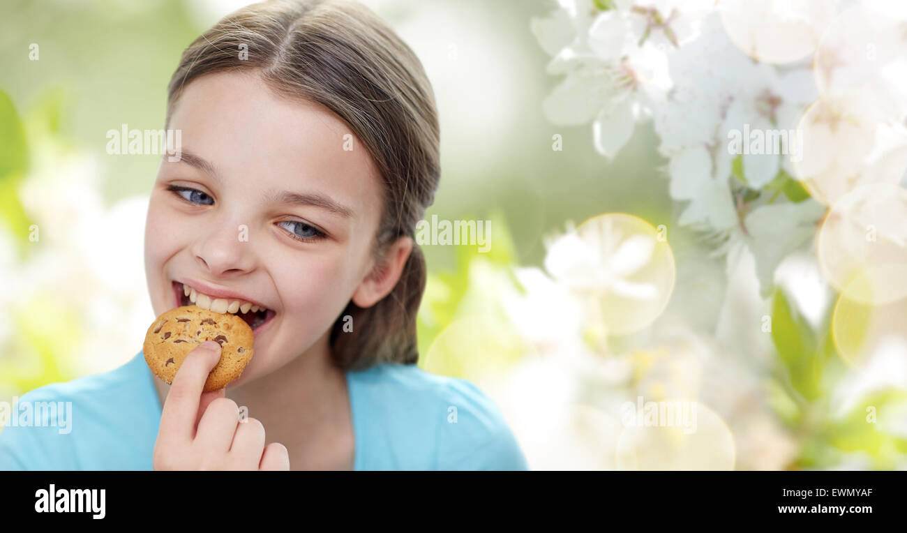 smiling little girl eating cookie or biscuit Stock Photo