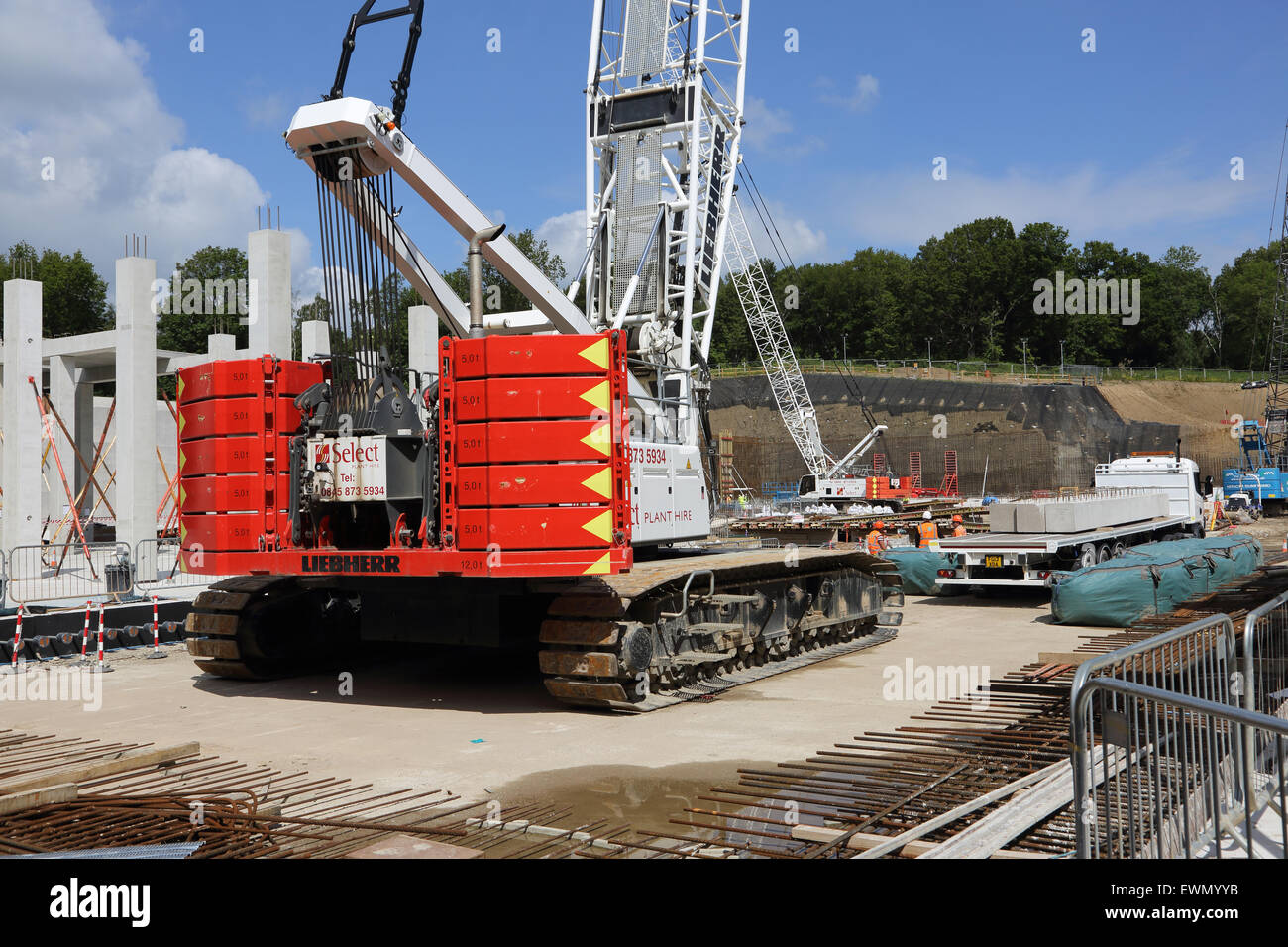 A leibherr LR series tracked crawler crane prepares to unload pre-cast concrete columns on a large construction site Stock Photo