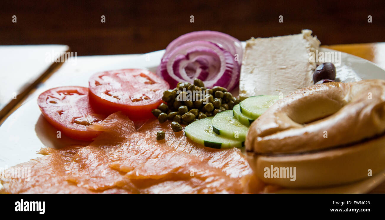 Nice plate of smoked salmon and bagel with garnishes backlit in window light Stock Photo