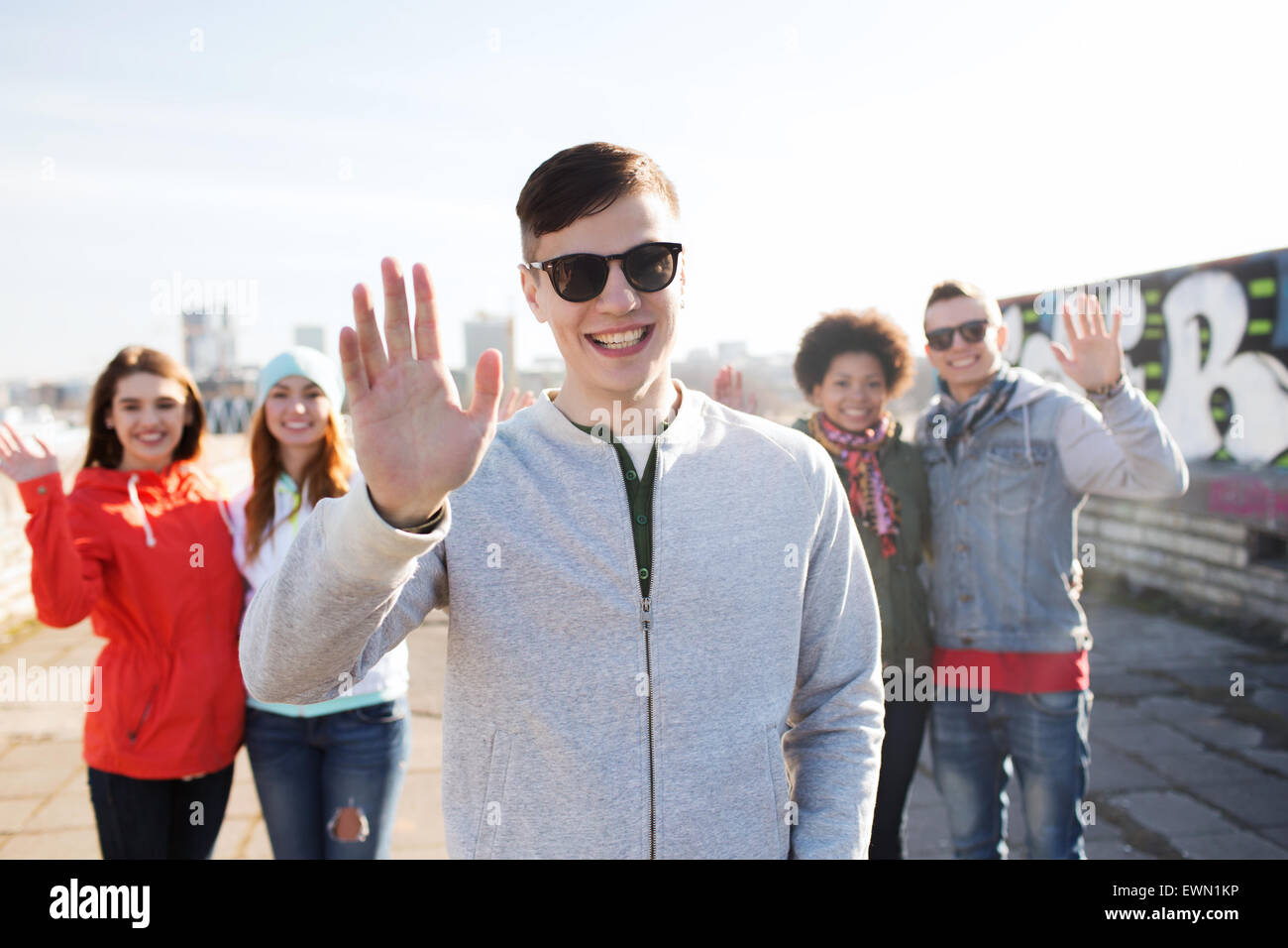 happy teenage friends waving hands on city street Stock Photo