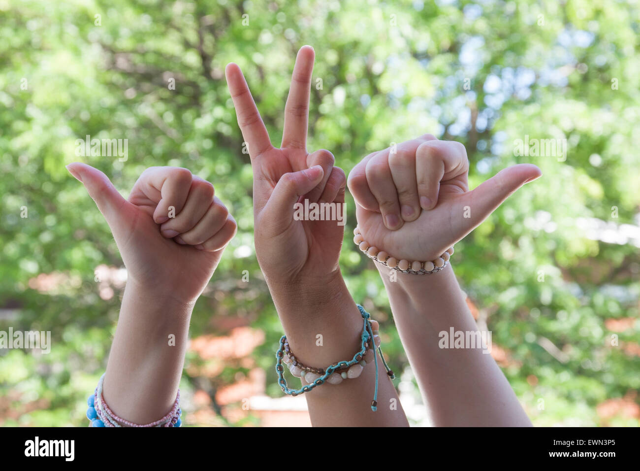Hand signs by three young girls. The unity of friendship is shown here by individuality. They have different ways to express in unity. Stock Photo