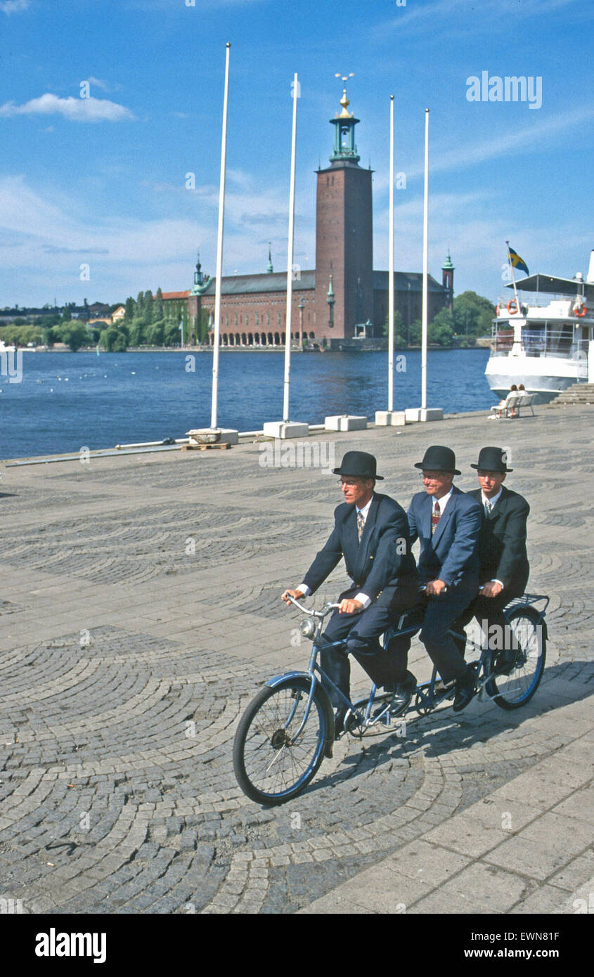 THREE BOWLER HATTED FIGURES ON ONE BICYCLE PHOTOGRAPHED IN STOCKHOLM SWEBEN Stock Photo