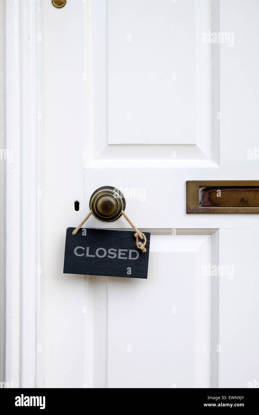 Small Closed Sign Hanging On A Brass Door Knob At The Entrance To
