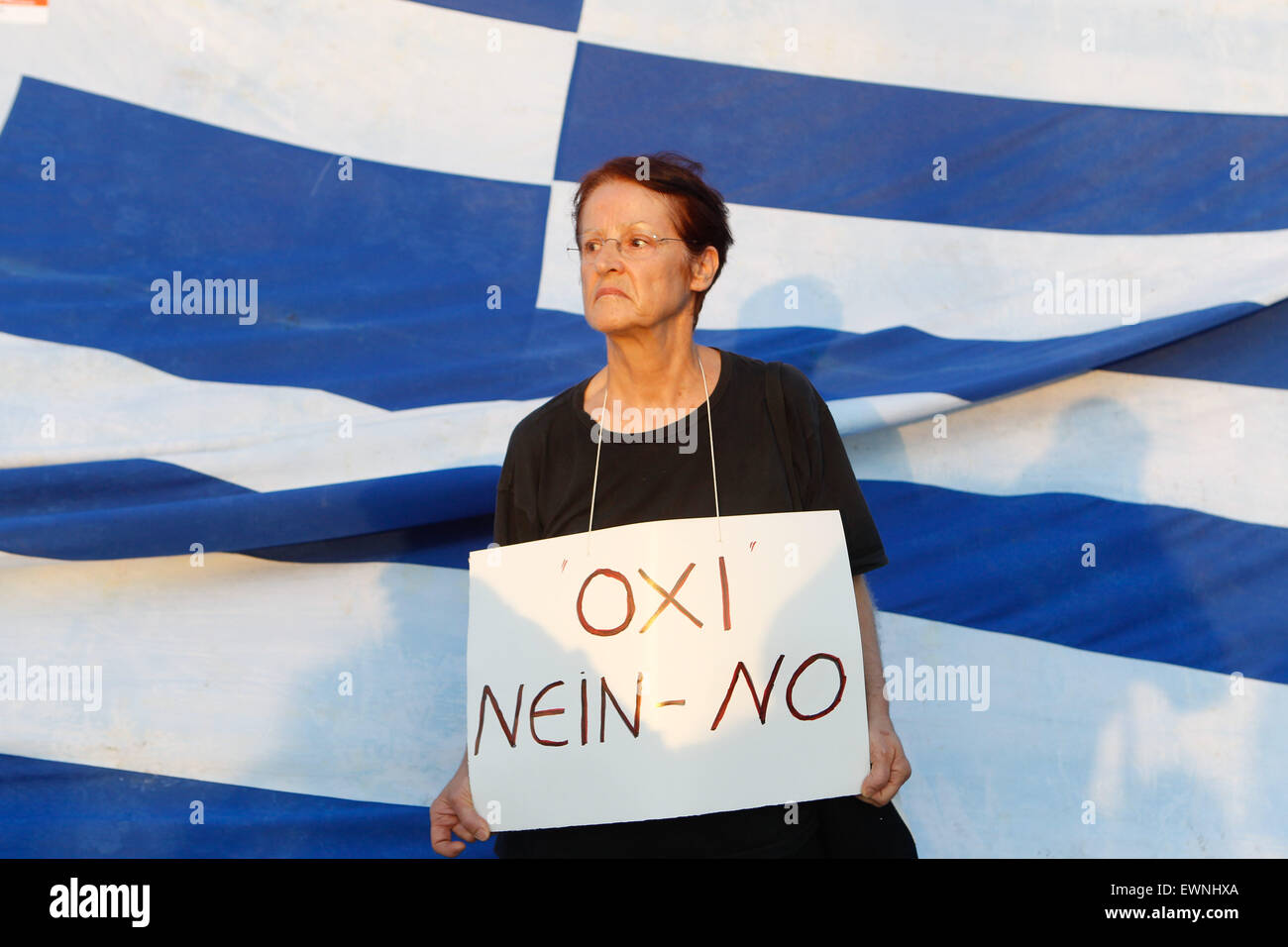 Athens, GREECE. 29th June, 2015. Supporters of the NO vote in the upcoming referendum hold a banner with colors of the Greek flag reading ''NO, OXI'' during a rally at Syntagma. Anxious Greek pensioners swarmed closed bank branches and long lines snaked outside ATMs as Greeks endured the first day of serious controls on their daily economic lives ahead of a July 5 referendum that could determine whether the country has to ditch the euro currency and return to the drachma. © Aristidis Vafeiadakis/ZUMA Wire/Alamy Live News Stock Photo