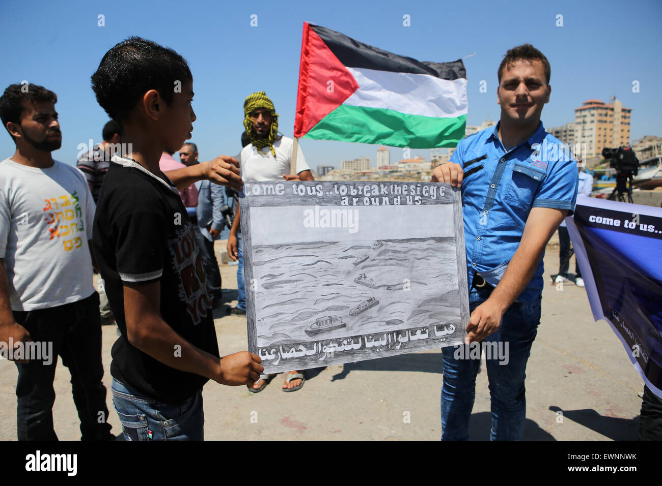 Gaza, Palestine. 29th June, 2015. Palestinians hold banner during a protest against the Israeli blocking of a boat of foreign activists from reaching Gaza, at the seaport of Gaza city. © Ibrahim Khatib/Pacific Press /Alamy Live News Stock Photo