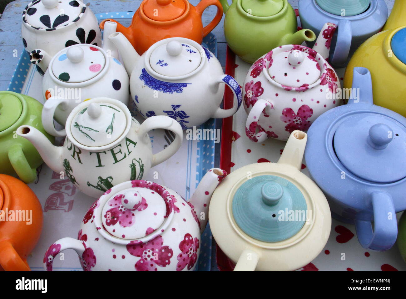 A collection of colourful teapots on a table at an outdoor tearoom at a British summer festival celebrating vintage style, England, UK Stock Photo