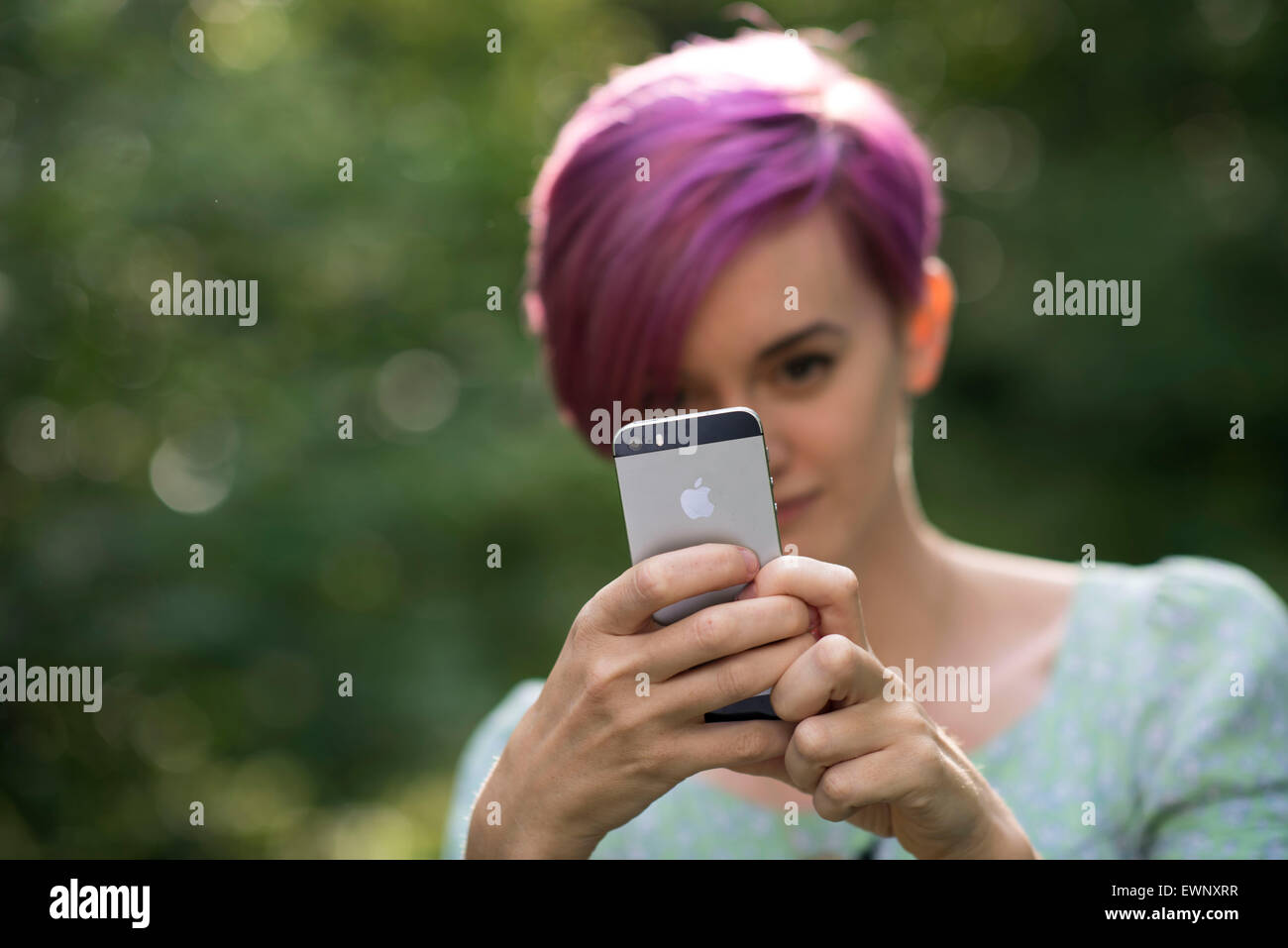 A girl using an Apple iPhone to take a picture. Stock Photo