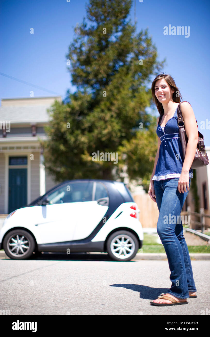 Young, tall woman standing in front of a very small car Stock Photo - Alamy