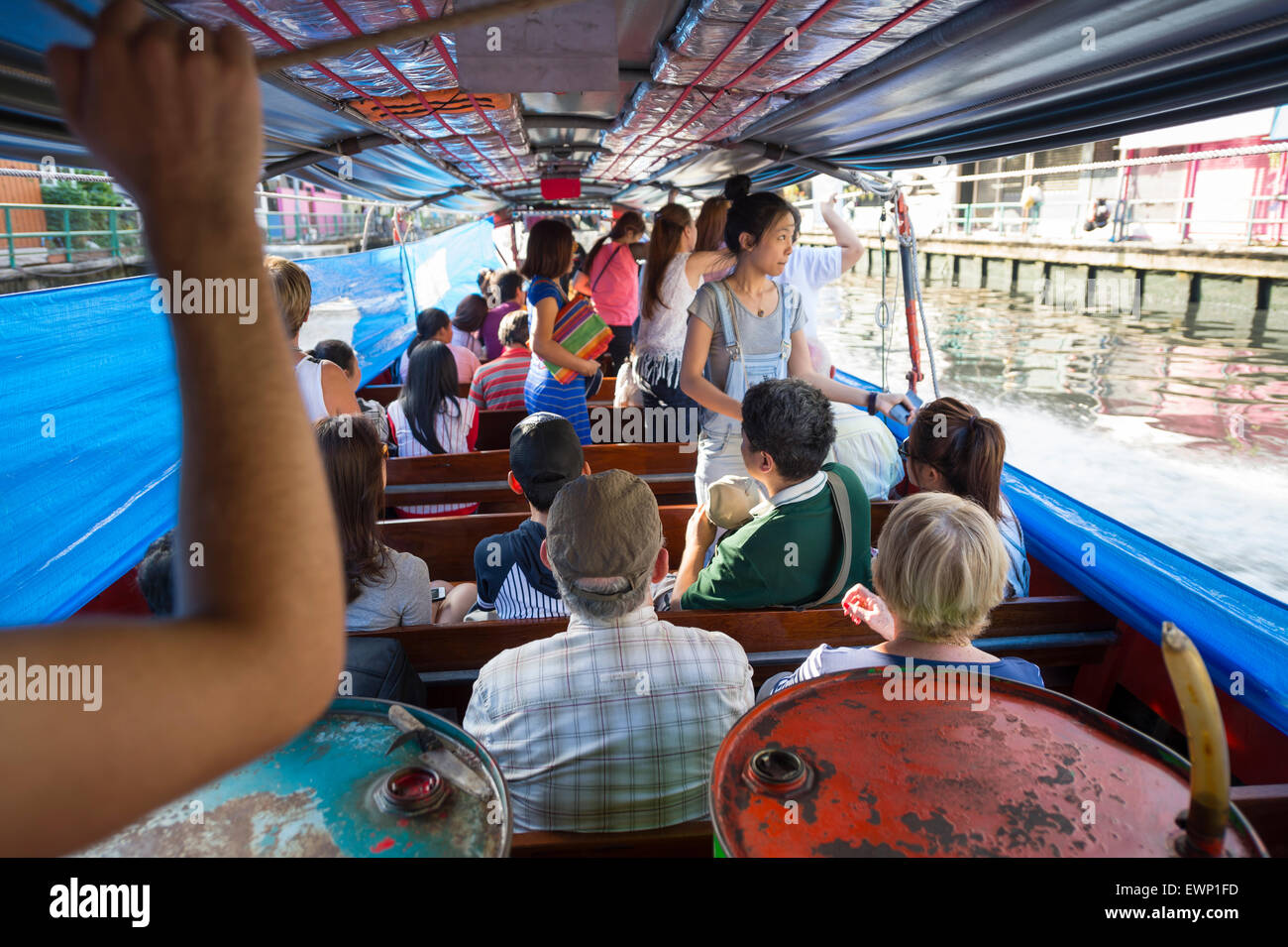 BANGKOK, THAILAND - NOVEMBER 17, 2014: Passengers ride a traditional khlong boat along one of the city's many canals. Stock Photo