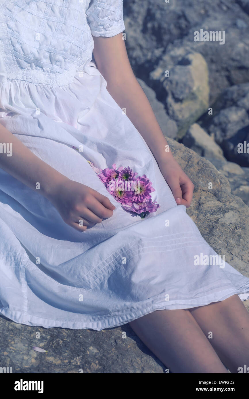 a girl is holding flower blossoms in her lap Stock Photo