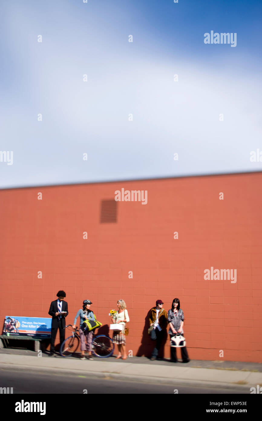 Five adults waiting for the bus in an urban area Stock Photo