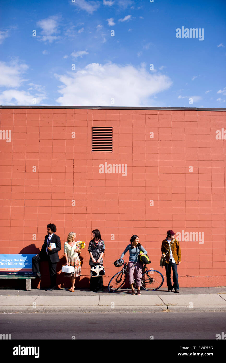Five adults waiting for the bus in an urban area Stock Photo