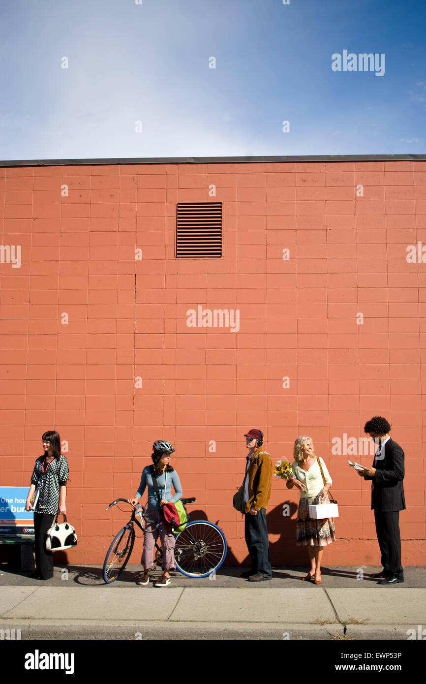 Five adults waiting for the bus in an urban area Stock Photo