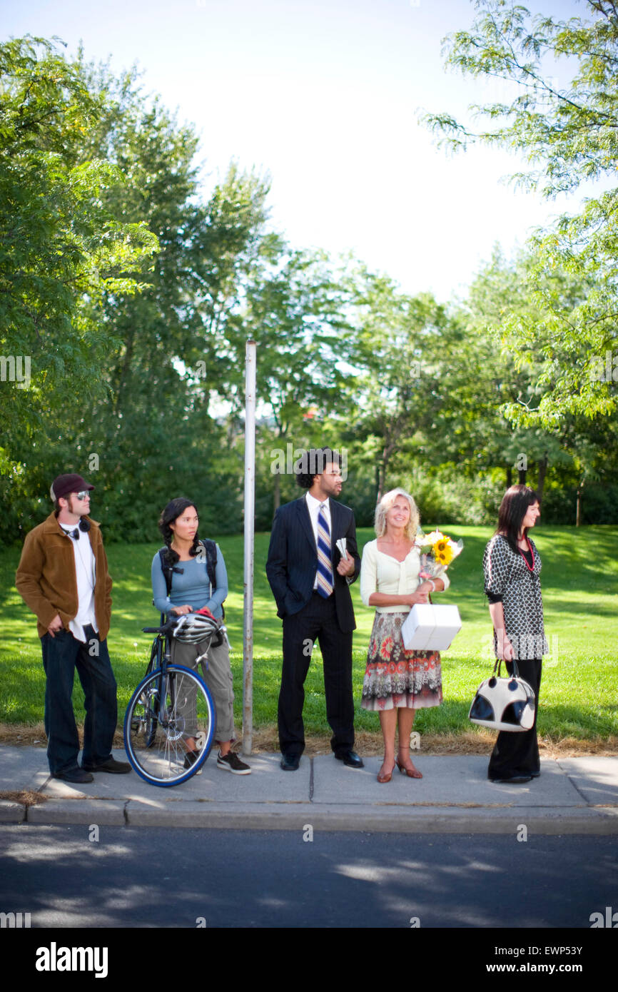 Five adults waiting for the bus in an urban area Stock Photo