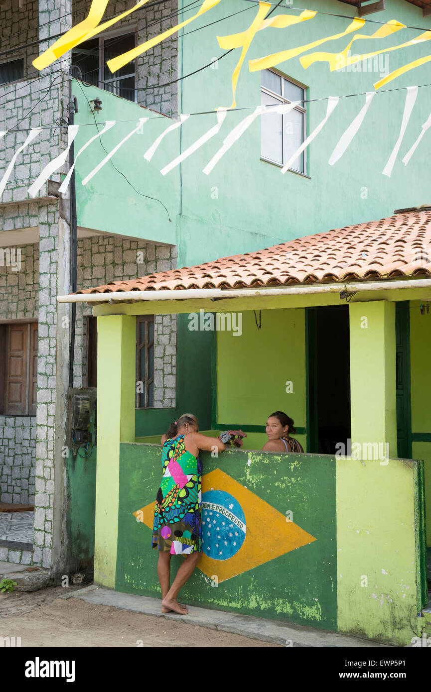 BAHIA, BRAZIL - MARCH 17, 2015: Brazilians in a small Northeastern fishing village talk over wall decorated with Brazilian flag. Stock Photo
