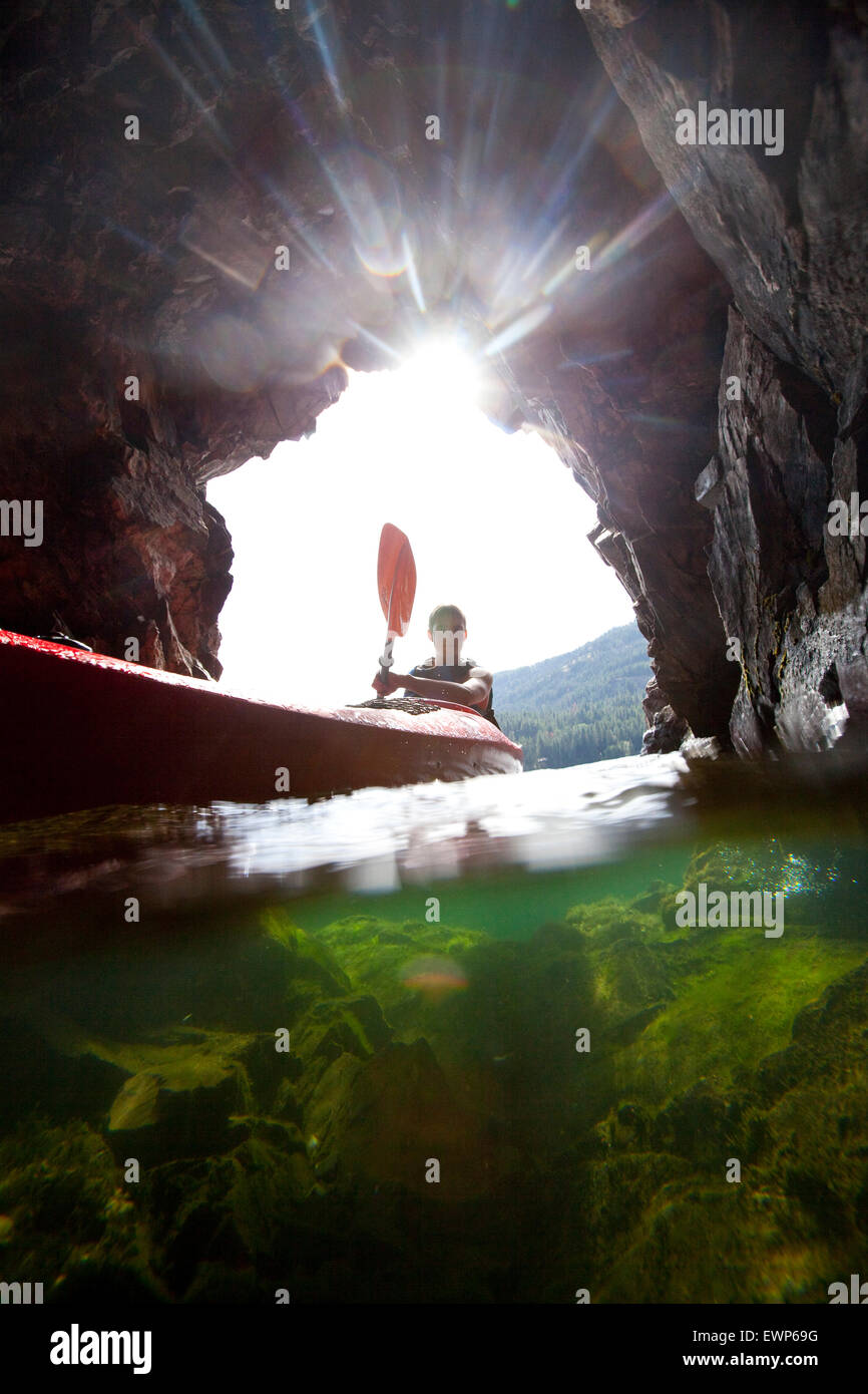 Over under view of a sa kayaker paddling in a small cave Stock Photo
