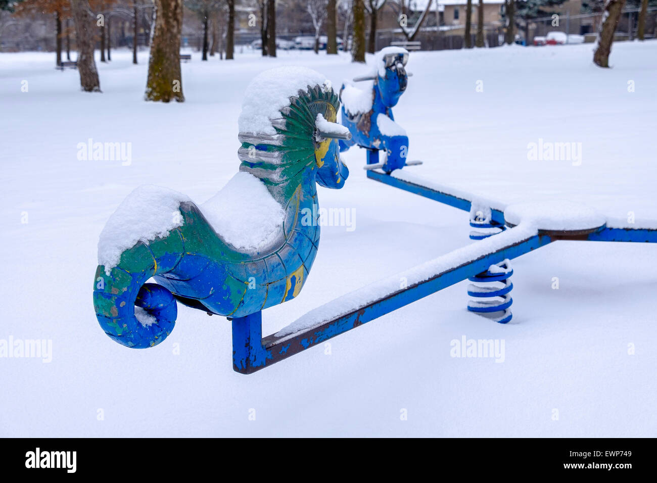 Blue and Green playground seahorses on a merry-go-round during a snowfall in Oklahoma City, Oklahoma, USA. Stock Photo