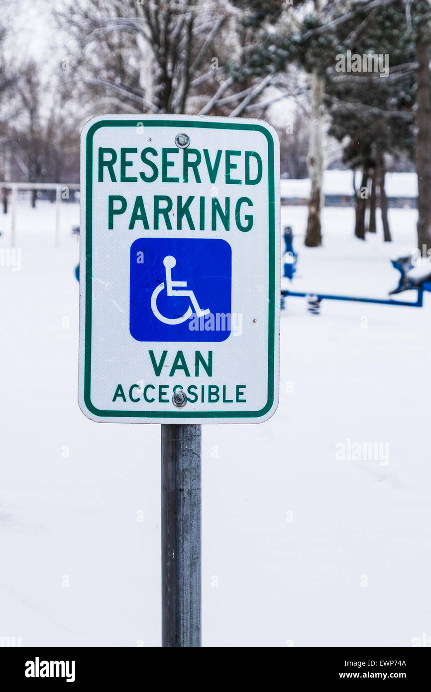 A handicapped parking sign in front of a snow covered playground in Bethany, Oklahoma, USA. Stock Photo
