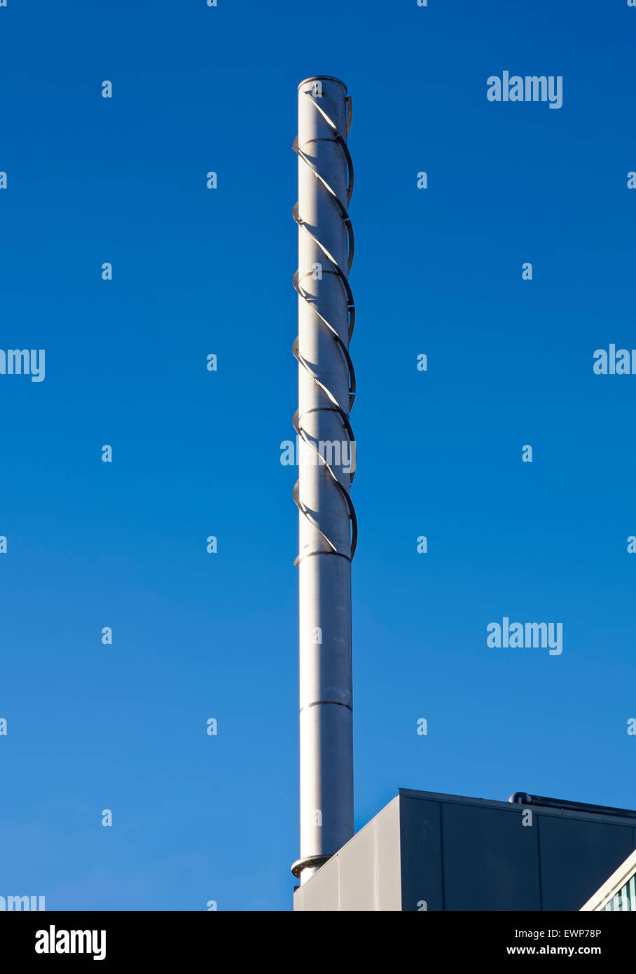 Metal factory chimney showing vortex-shedding strake wraps Stock Photo