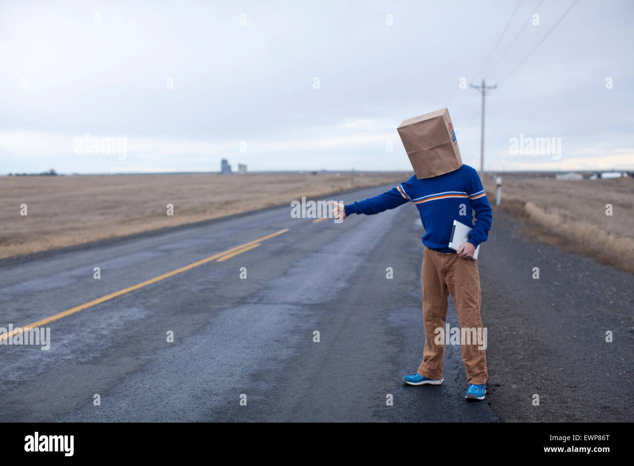 Funny image of a man hitchhiking with a paper bag over his head Stock Photo Alamy