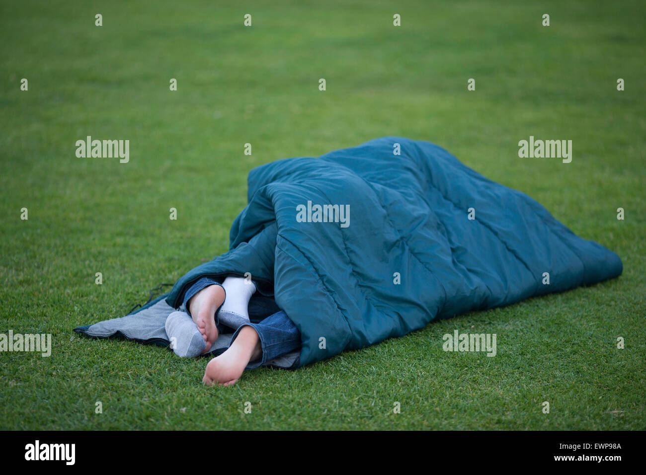 Two pairs of feet hanging out of sleeping bag. Stock Photo