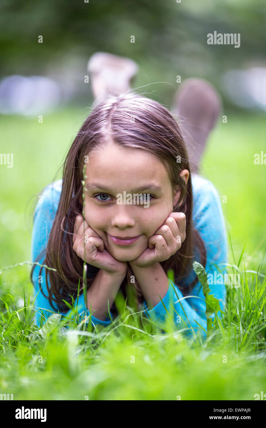 Portrait of cute little girl lying in green grass. Stock Photo