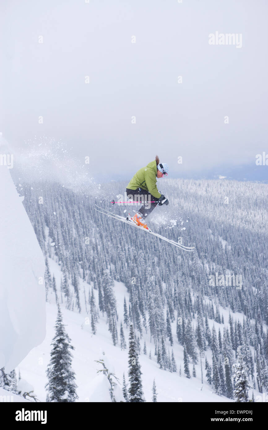 Female skier jumping off cornice Stock Photo